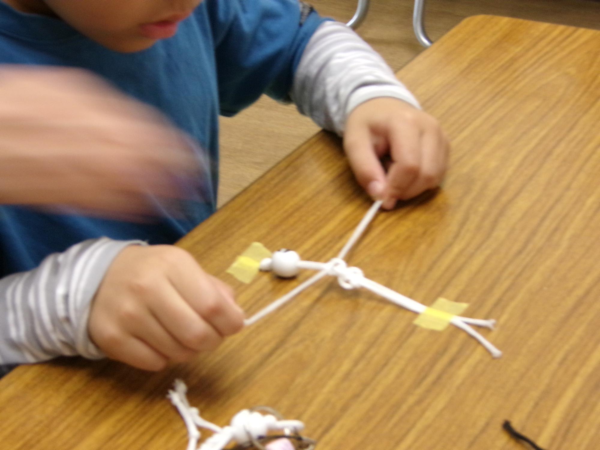 紐を編んでガイコツの身体の部分を作っている写真