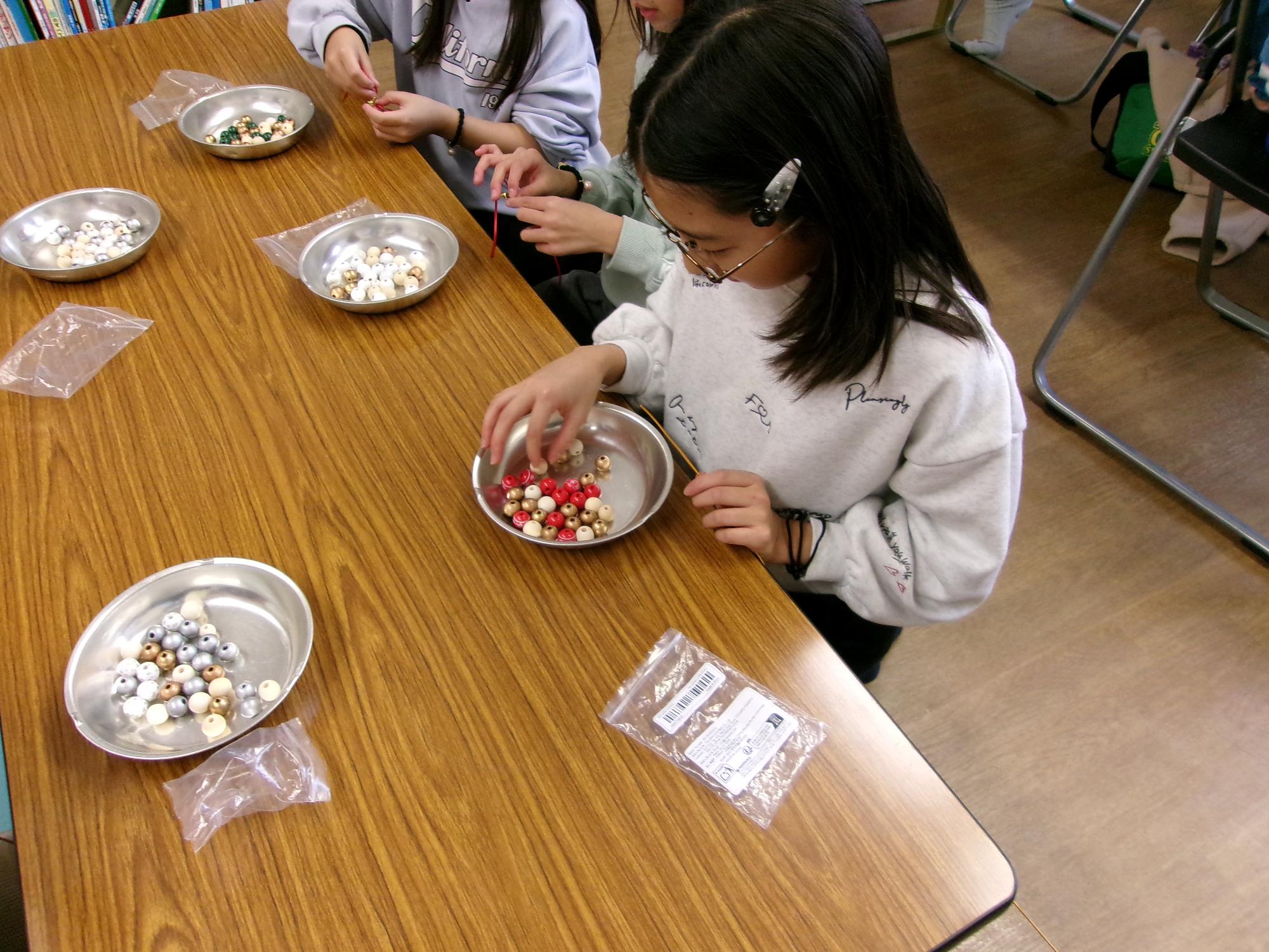 子どもたちがお皿にウッドビーズを移し入れている写真