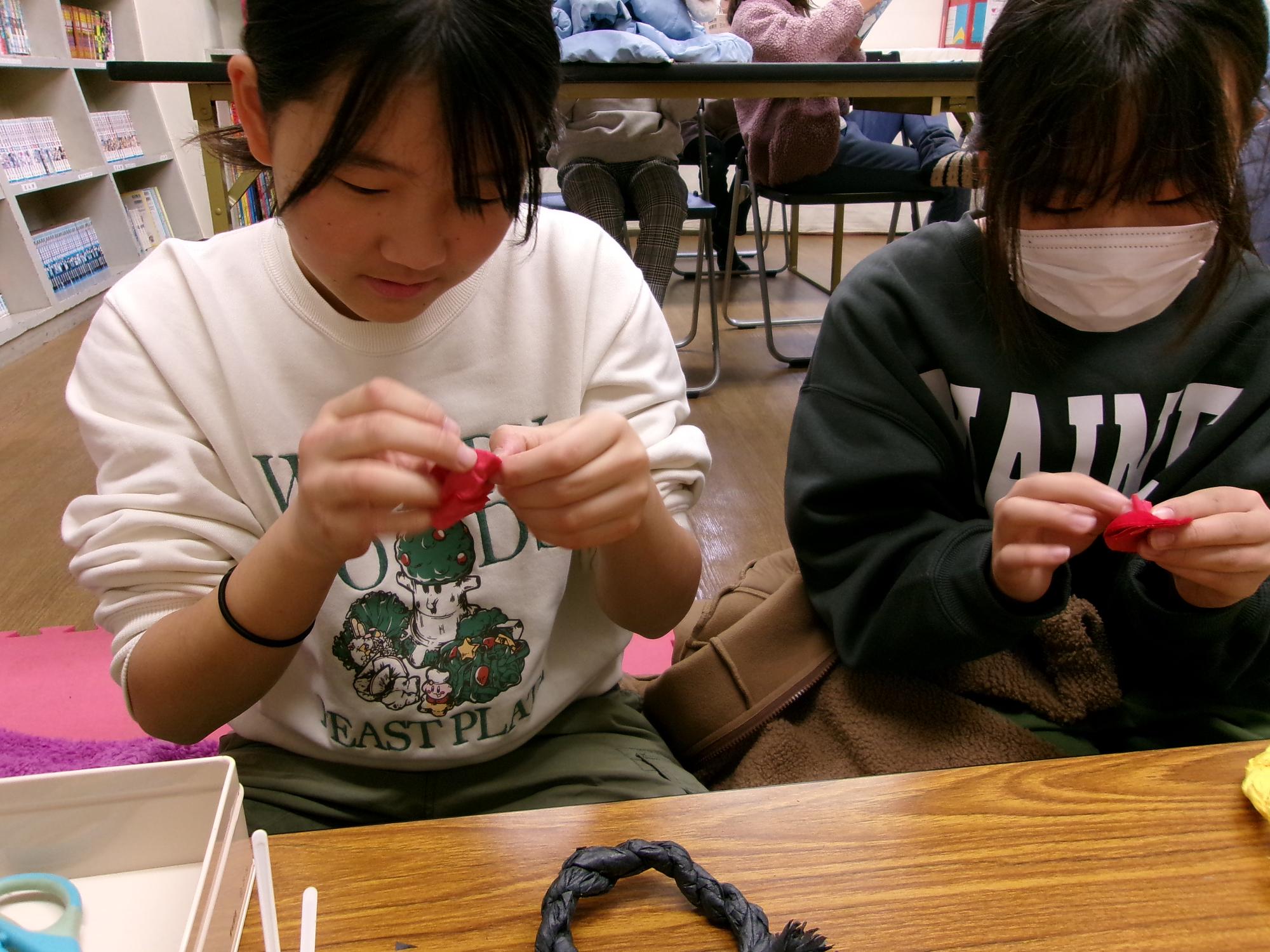 女の子が飾りに使用する花を作っている写真