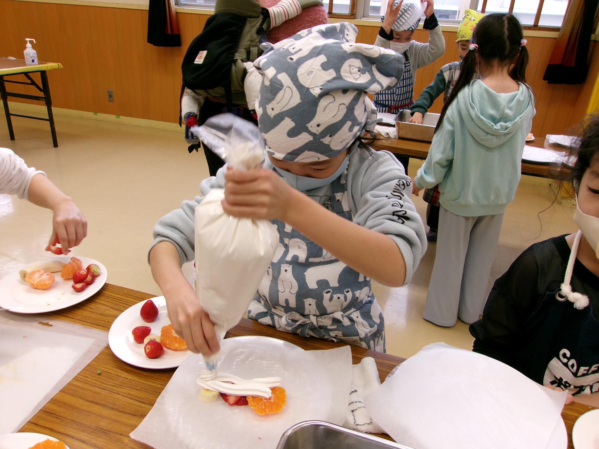 子どもが生クリームを絞っている写真