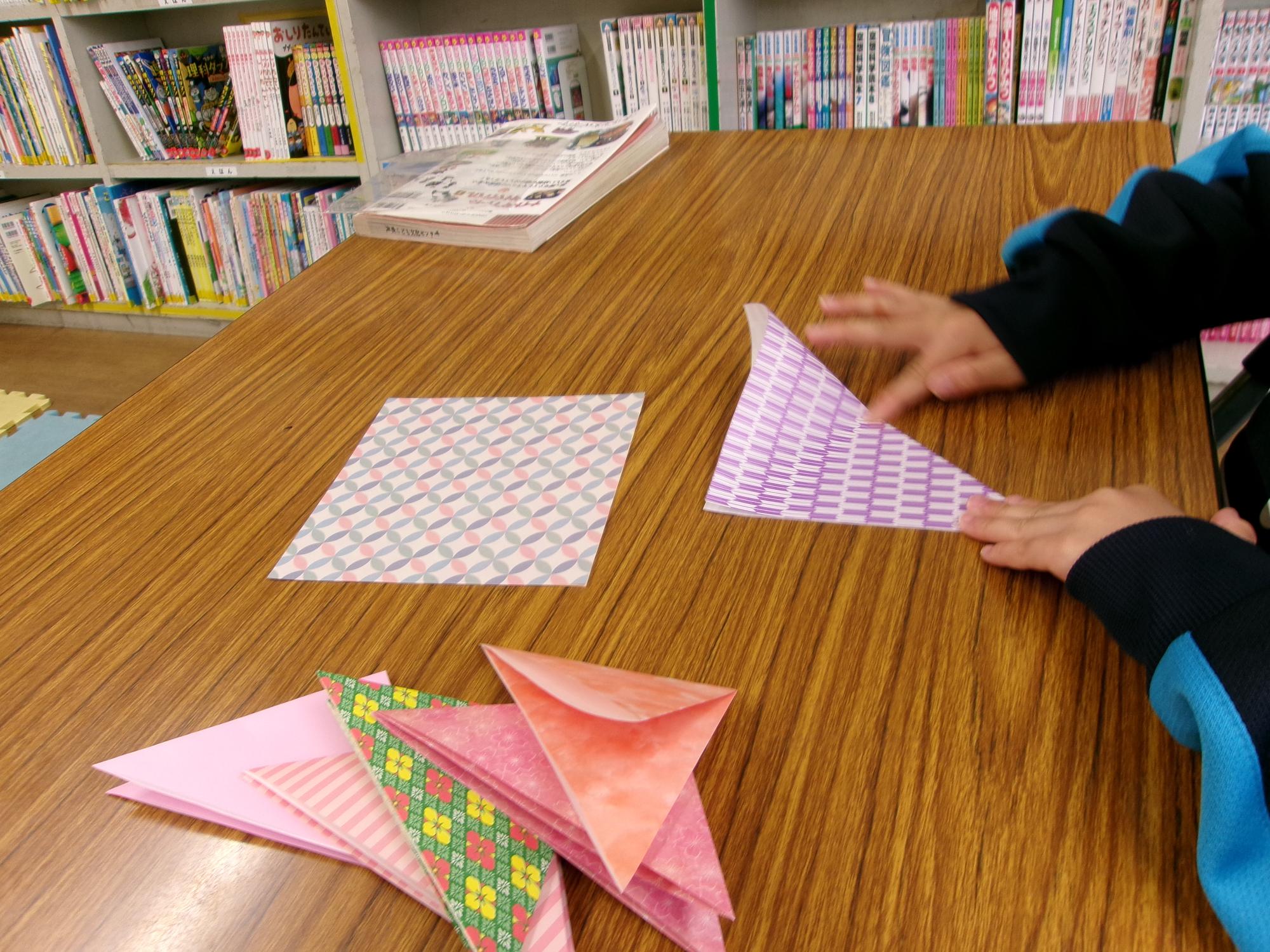 こどもが三角に折り紙を折っている写真