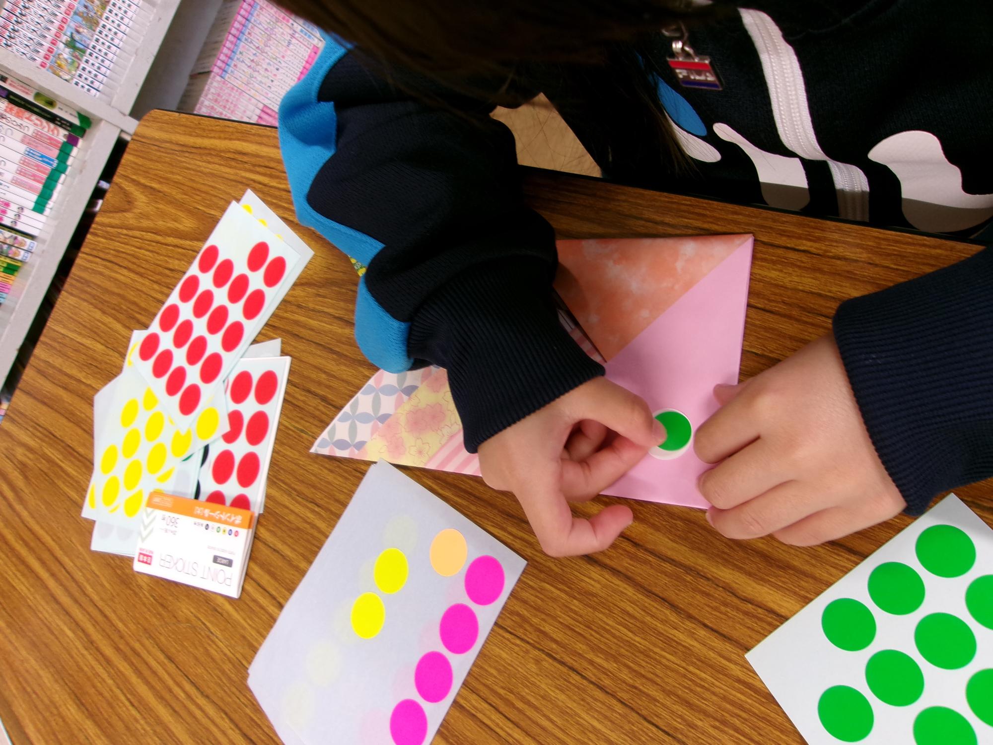 女の子がこいのぼりの目の部分を作っている写真