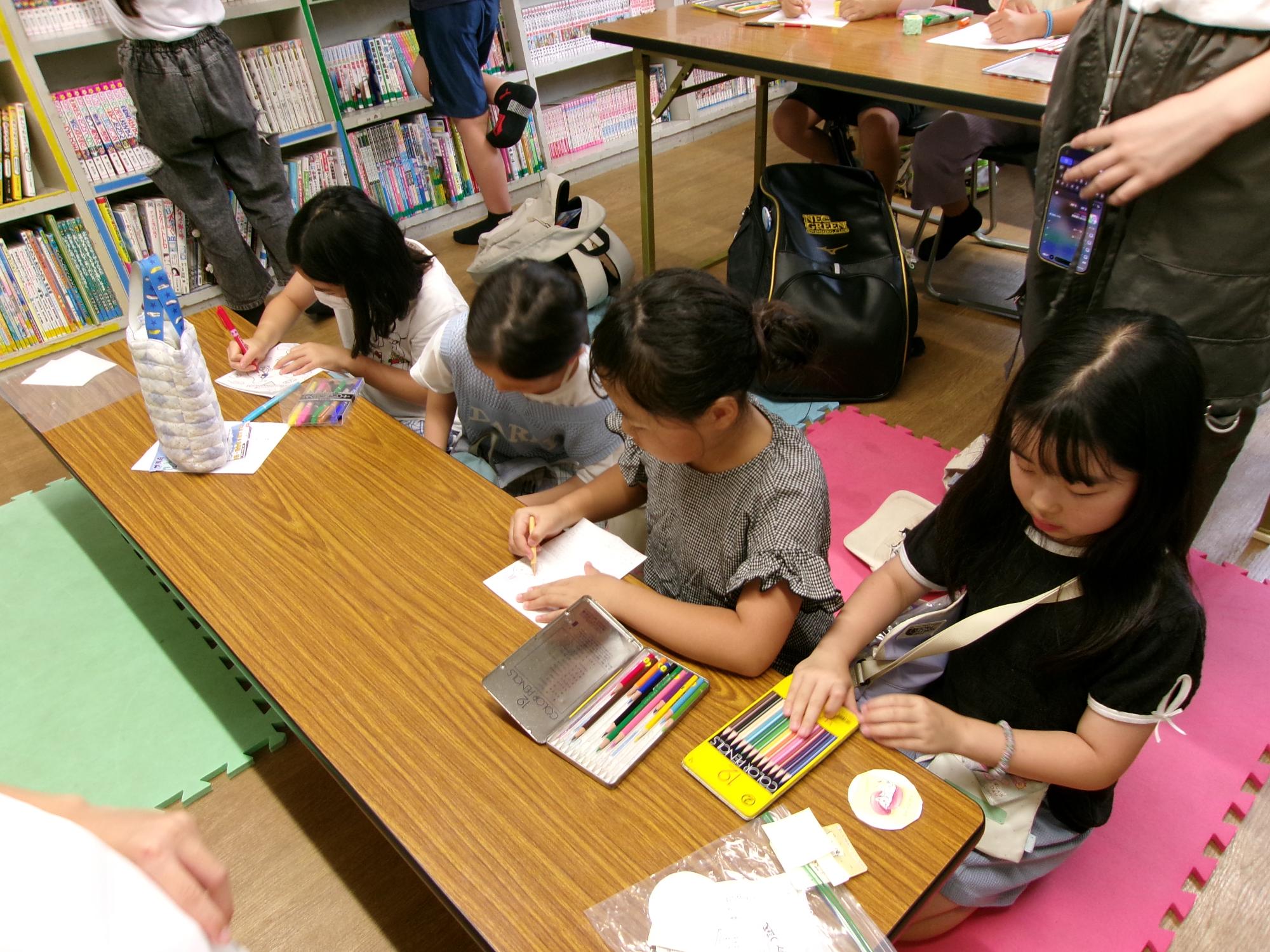 子どもたちが缶バッチにする絵を描いている写真