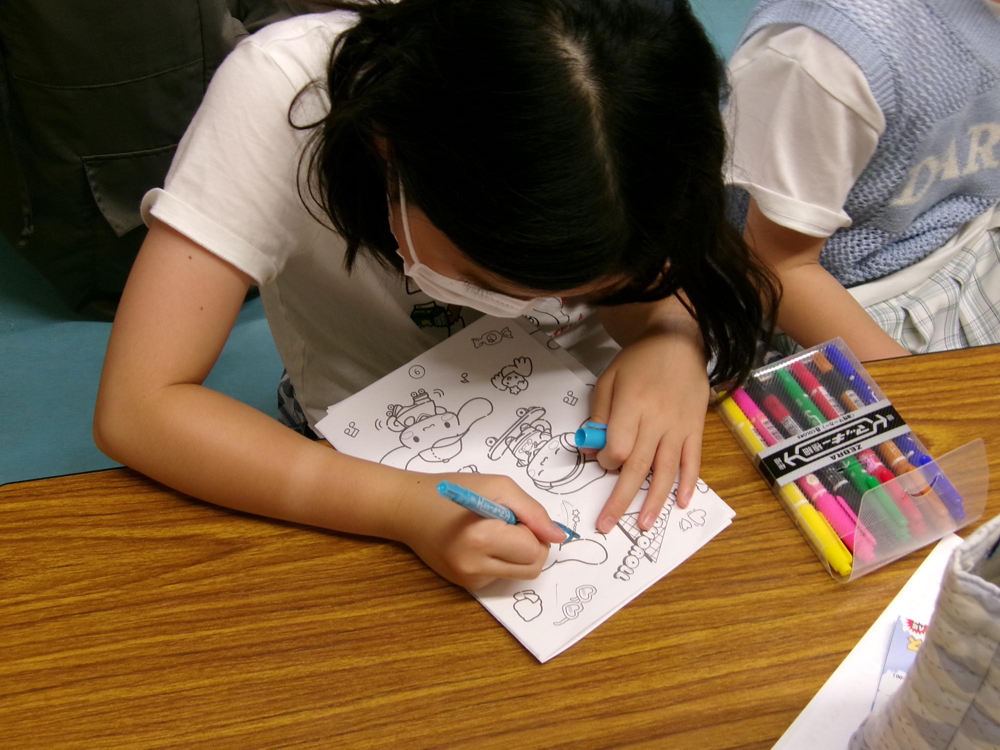 女の子がバッチにする絵に色を塗っている写真