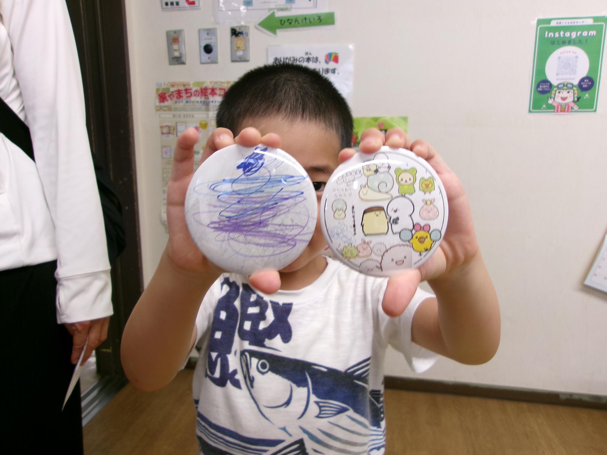 完成した缶バッチを見せてくれている幼児さんの写真