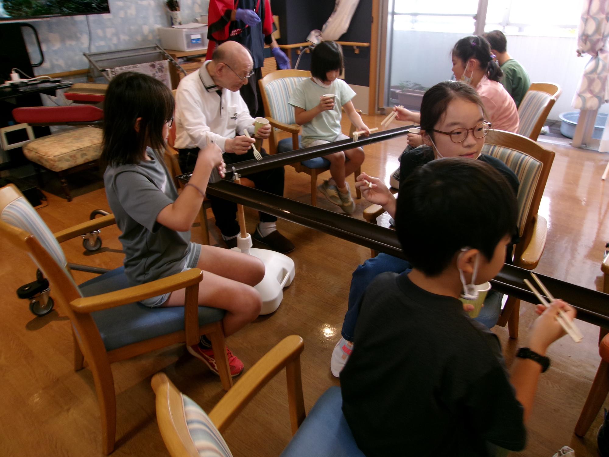 子どもたちが流しそうめんを食べている写真