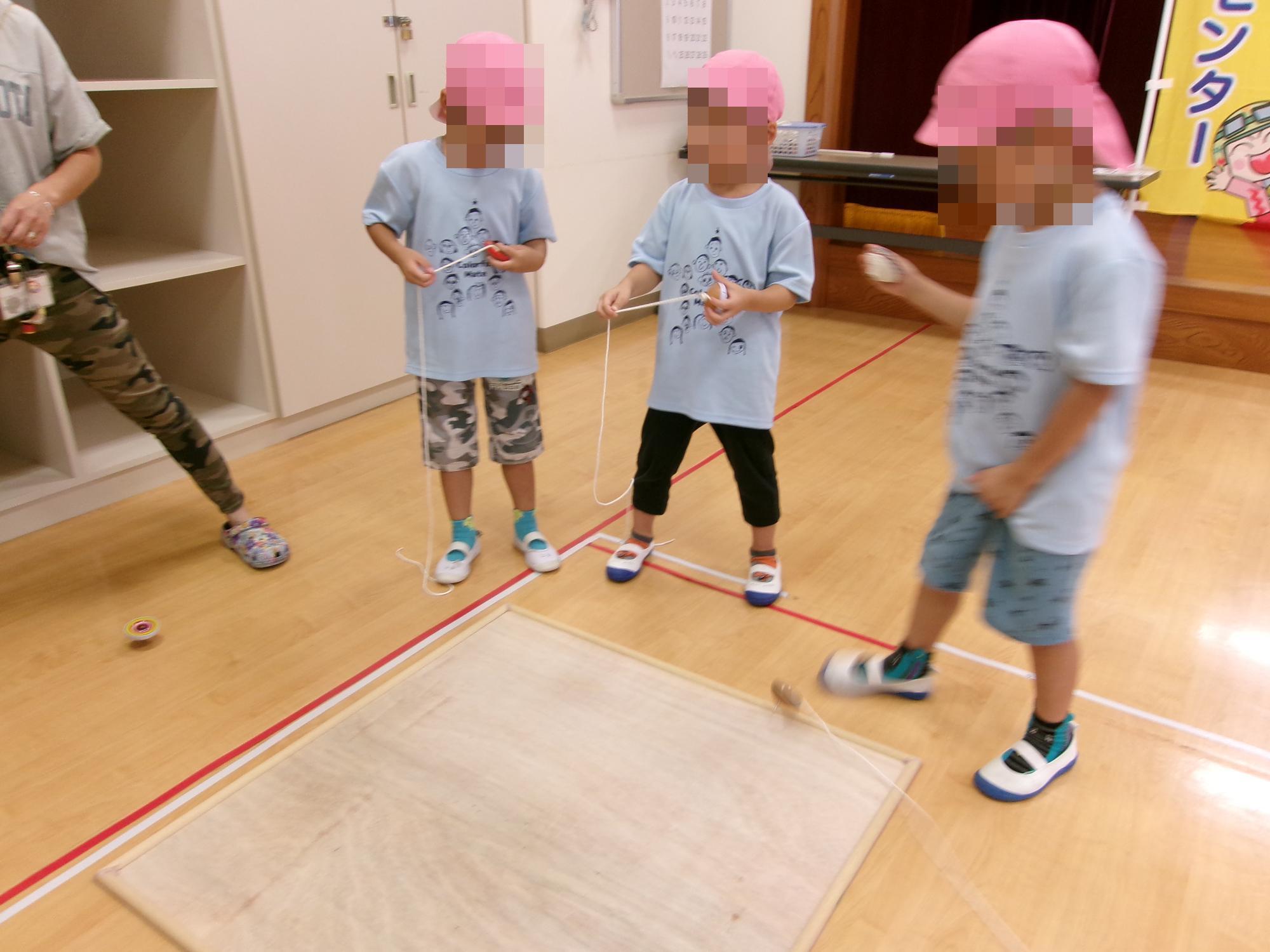 保育園児三名がコマをやっている写真