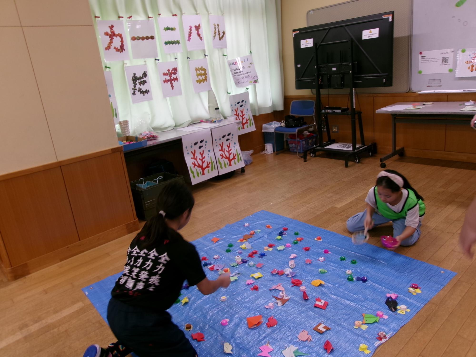 子どもたちが魚すくいのゲームを行っている写真