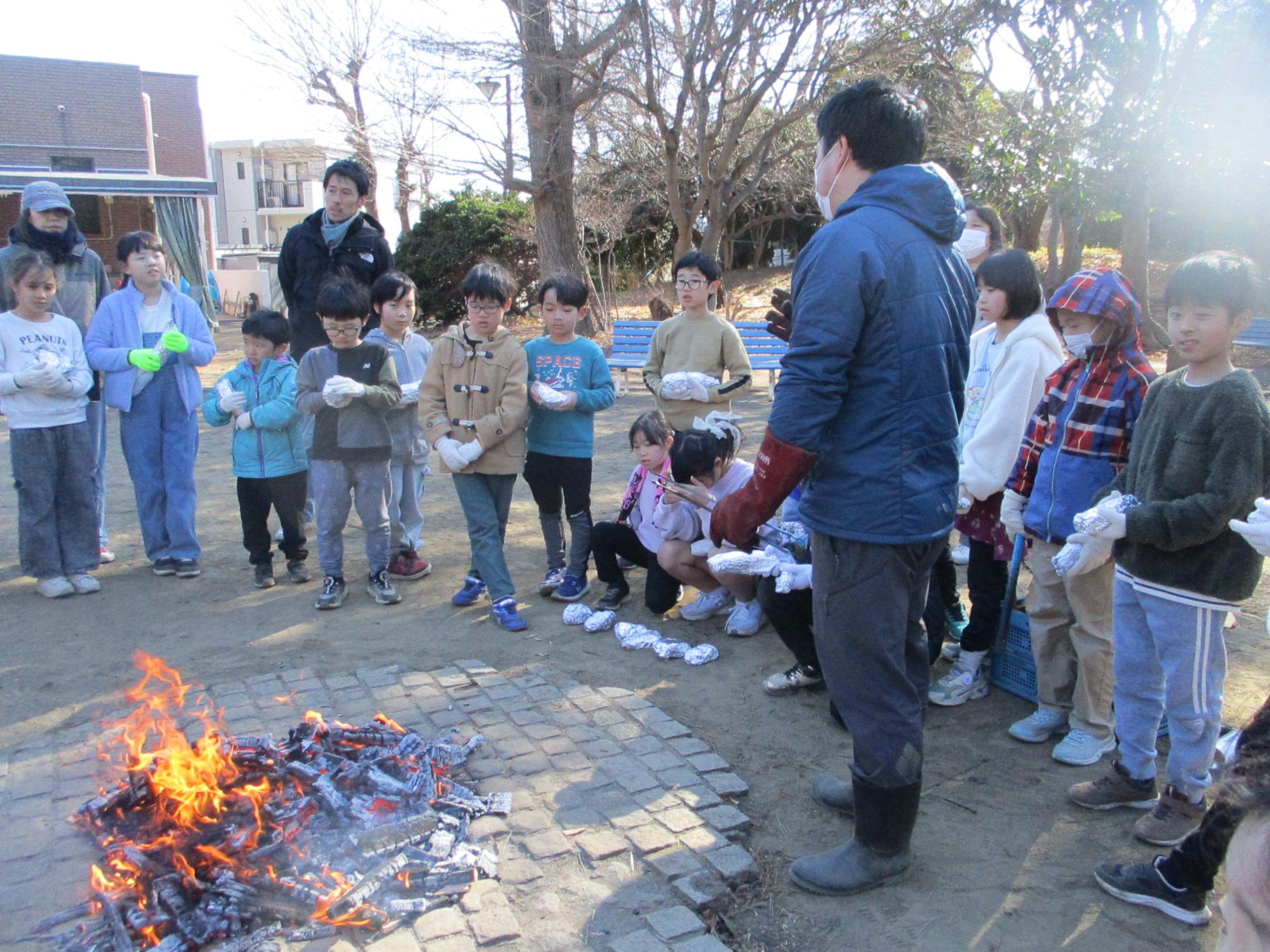 焼き芋を焼く指導を受けている写真
