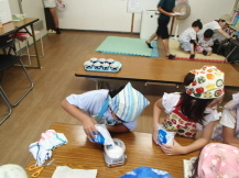 三角巾を被った子どもたちが長机の上で塩を計っている写真