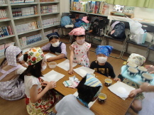 三角巾とエプロンを身につけた子どもたちが、長机の前に座っている写真