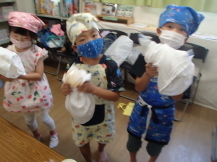 子どもたちがジュースを包んだ氷と塩の袋を元気よくシャカシャカと振っている写真