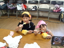 三角巾を被った二人の姉妹が、一緒に仲良くシャーベットを食べている写真