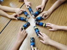 机の上に出来上がったコマを持って置いた9人の子どもたちの腕だけが映された写真