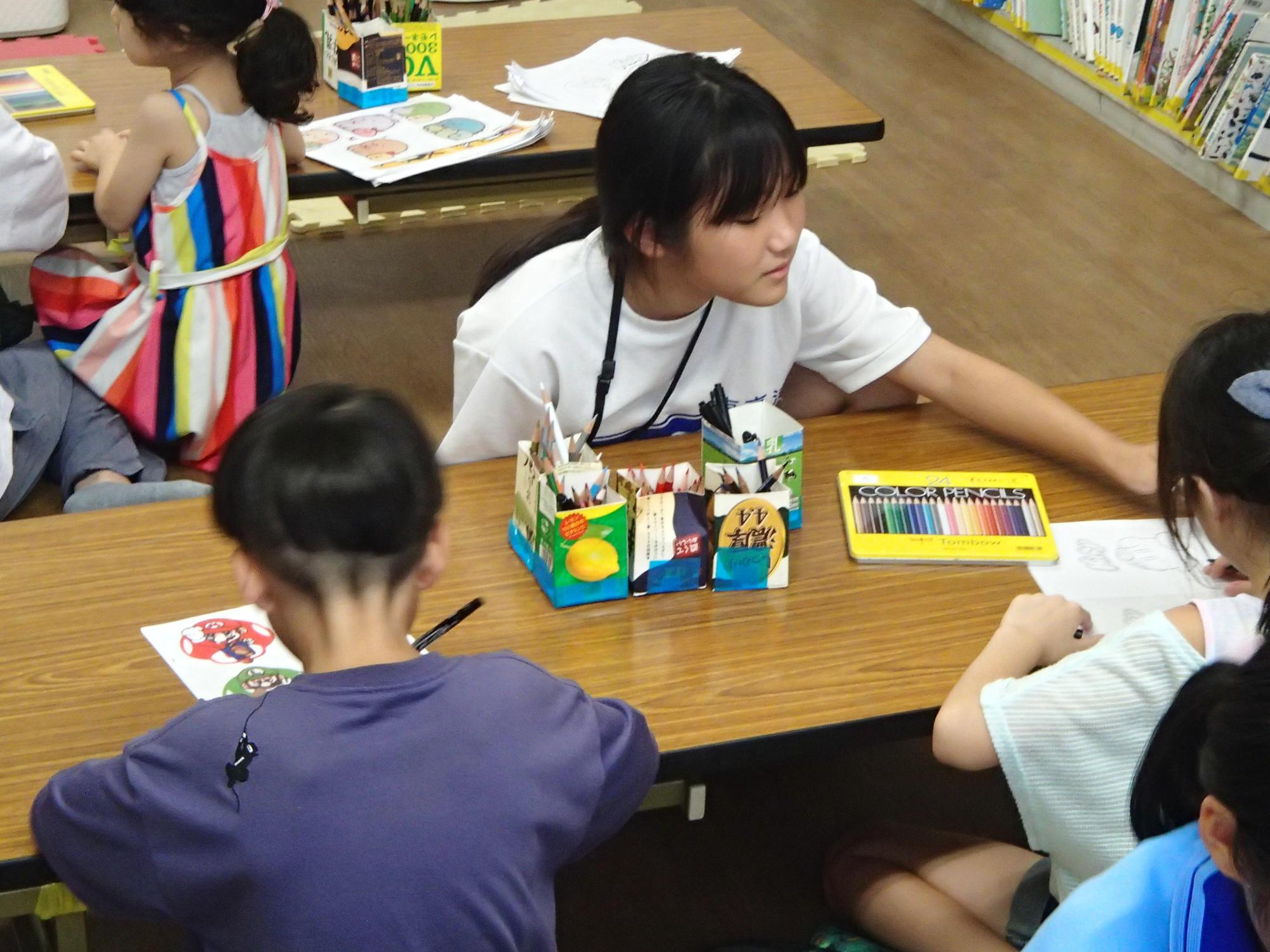 中学生がプラバン工作を小学生と一緒に行っている写真