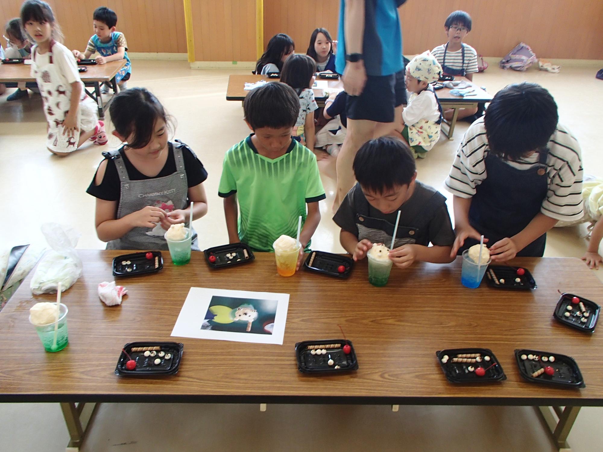 席に着いてトッピングを乗せている子どもたちの写真