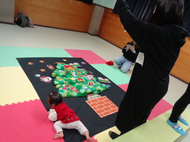 ツリーの飾りと赤ちゃんを一緒に撮ろうとしている写真