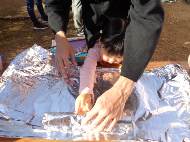 芋をアルミホイルで巻いている様子