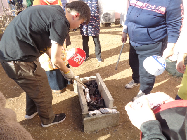 芋を炭の中に入れている様子