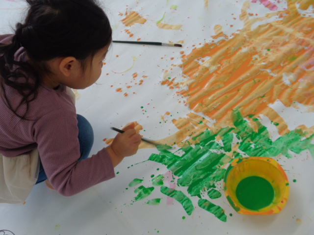 オレンジと緑の絵の具で絵を描いている