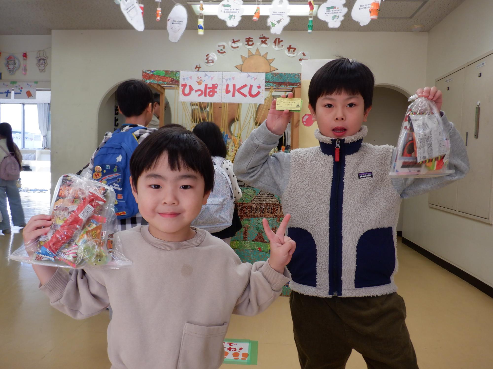 引っ張りくじの景品をもって笑顔で写真をとる参加児童