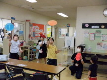 皿を器用に回す黄色い服の男の子を正面に周りで見ている大人と子供たちの写真