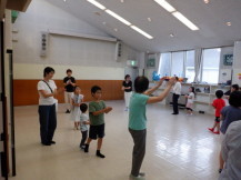 室内を時計回りに進みながら盆踊りの練習をする大人と子供の写真