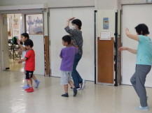 2人1組で盆踊りを踊る子供と大人たちを横から撮っている写真