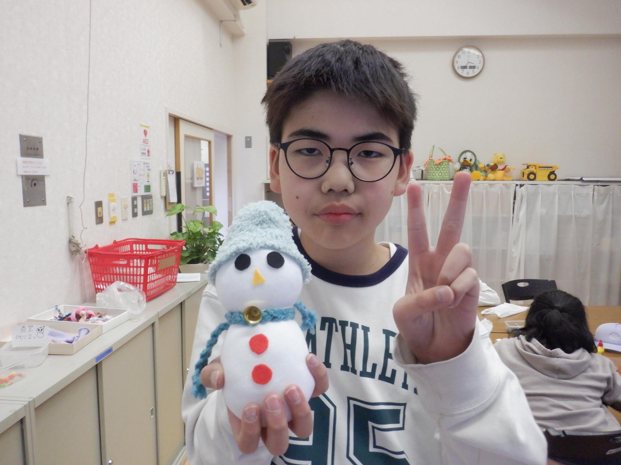 出来上がったソックスノーマンと記念撮影する小学生