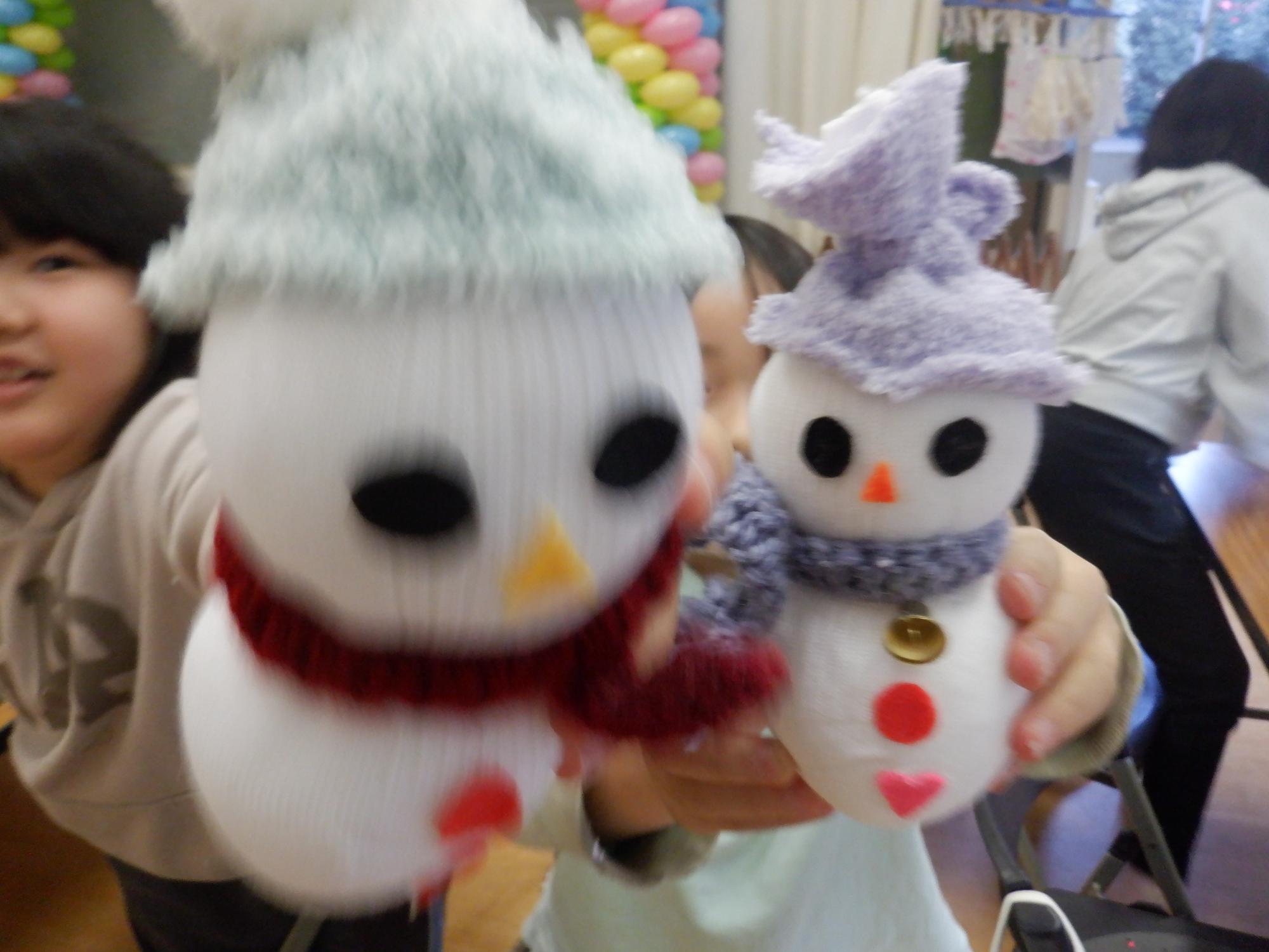 出来上がったソックスノーマンと記念撮影する小学生2人