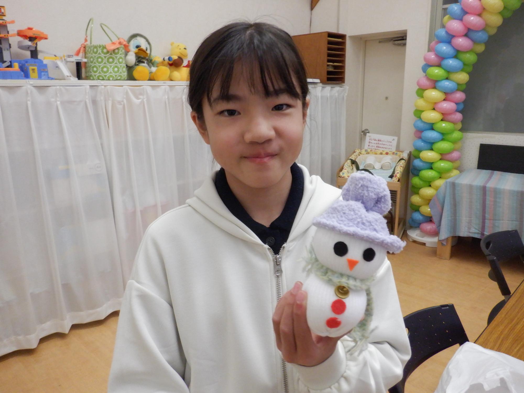 出来上がったソックスノーマンと記念撮影する小学生
