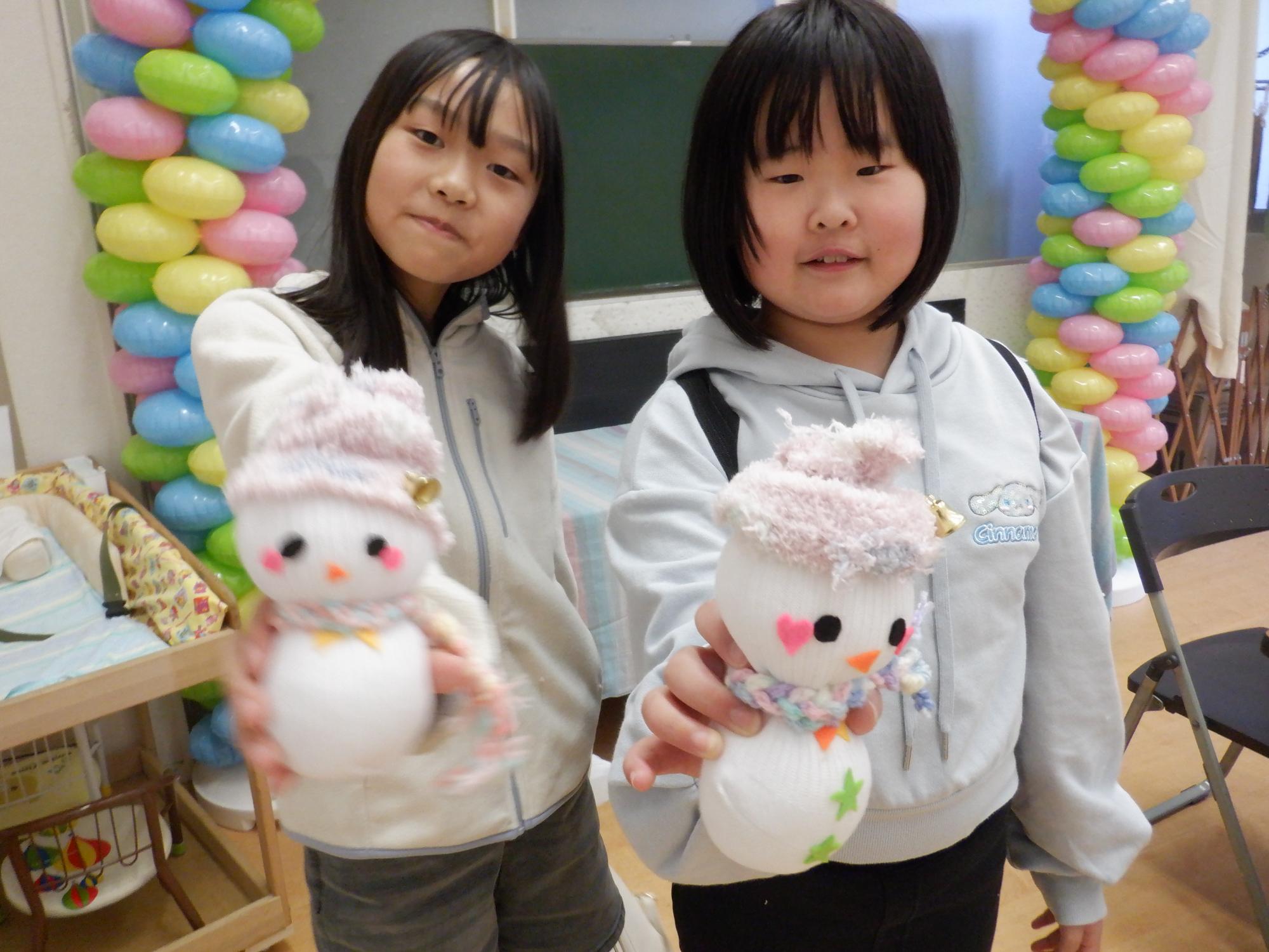 出来上がったソックスノーマンと記念撮影する小学生2人