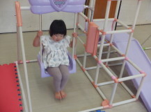 薄紫の滑り台付きブランコで遊ぶ女の子の写真