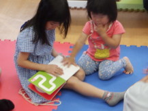 しかけ絵本を座って読んでいる2人の女の子の写真