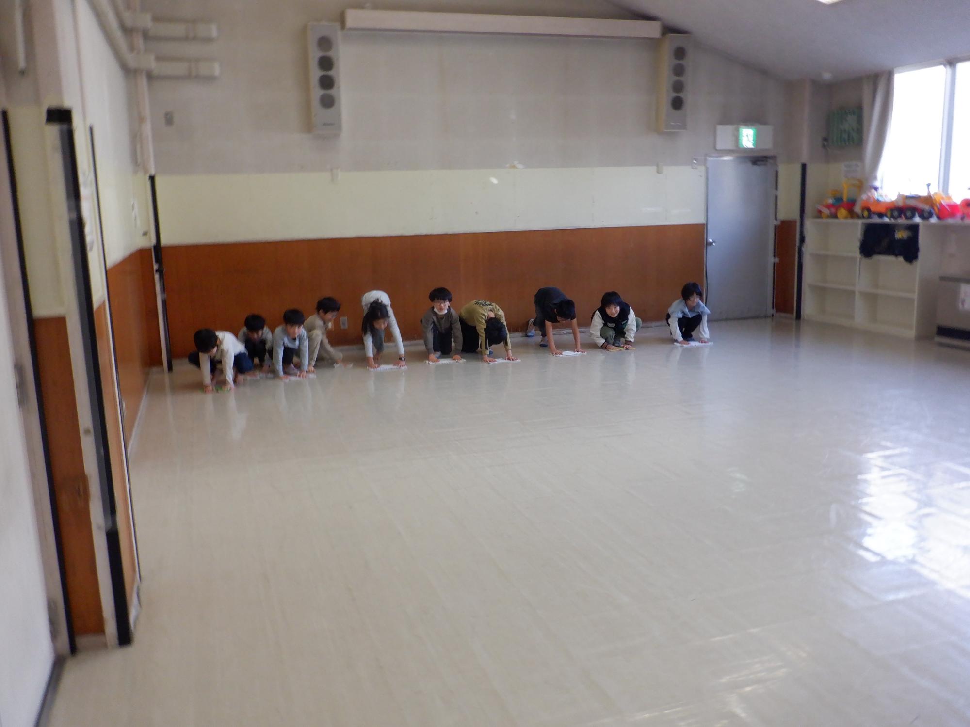 トレーニング室を雑巾がけする小学生達