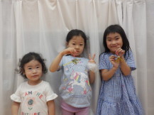 完成した作品をカメラに見せて撮影する3人の子供たちの写真