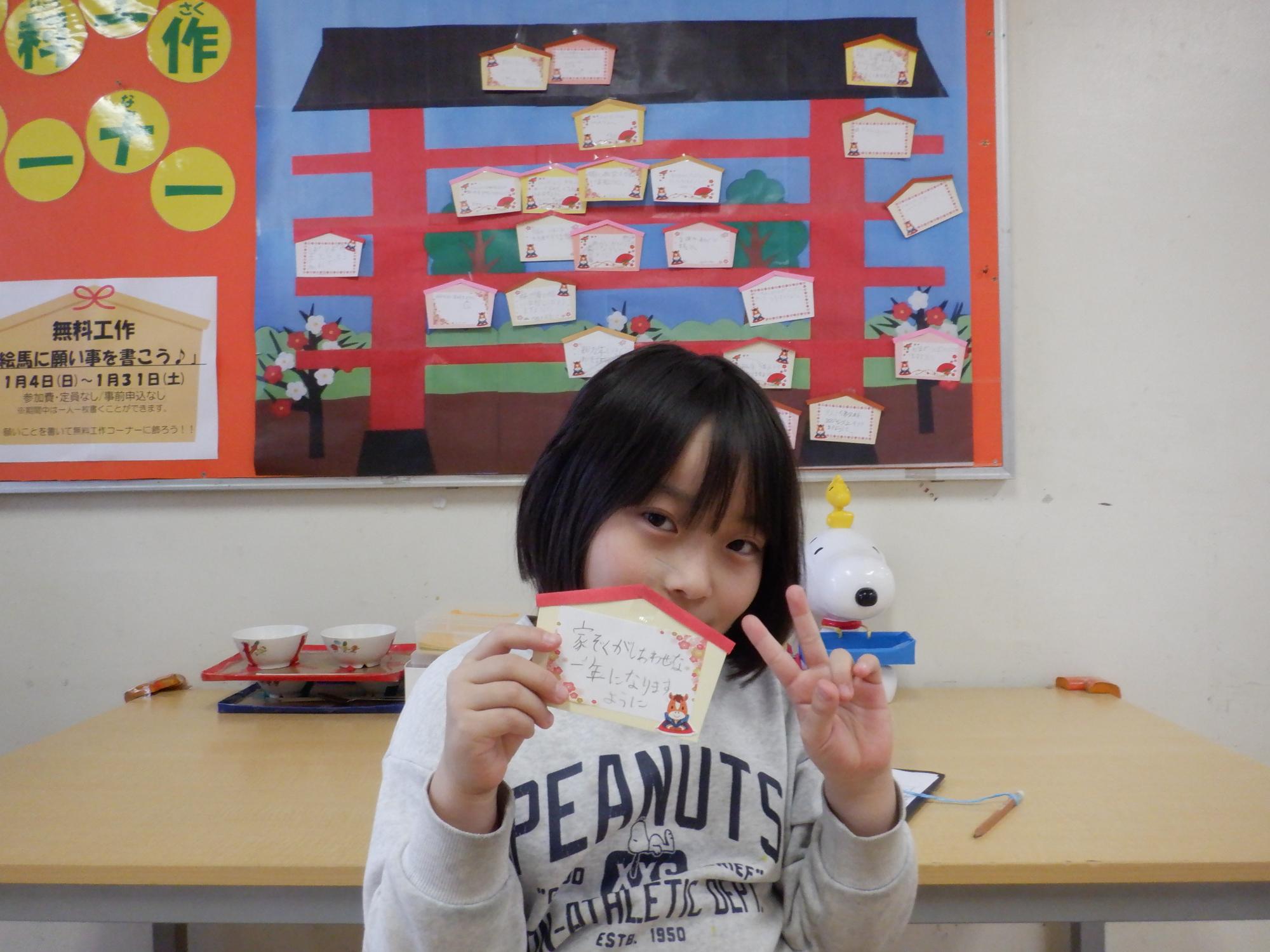 絵馬と一緒に写真を撮る小学生