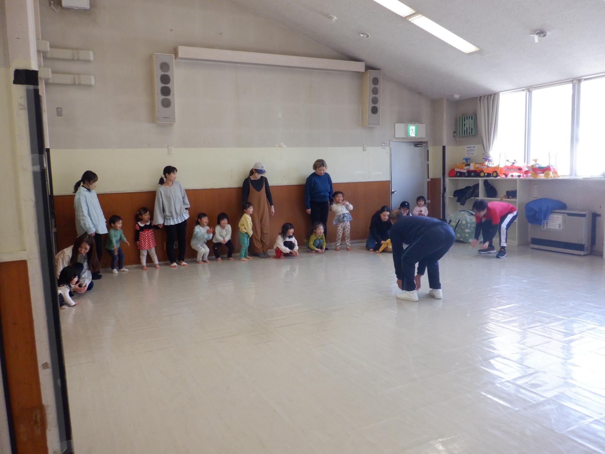 幼児と保護者が並んで先生の説明を聞いている様子