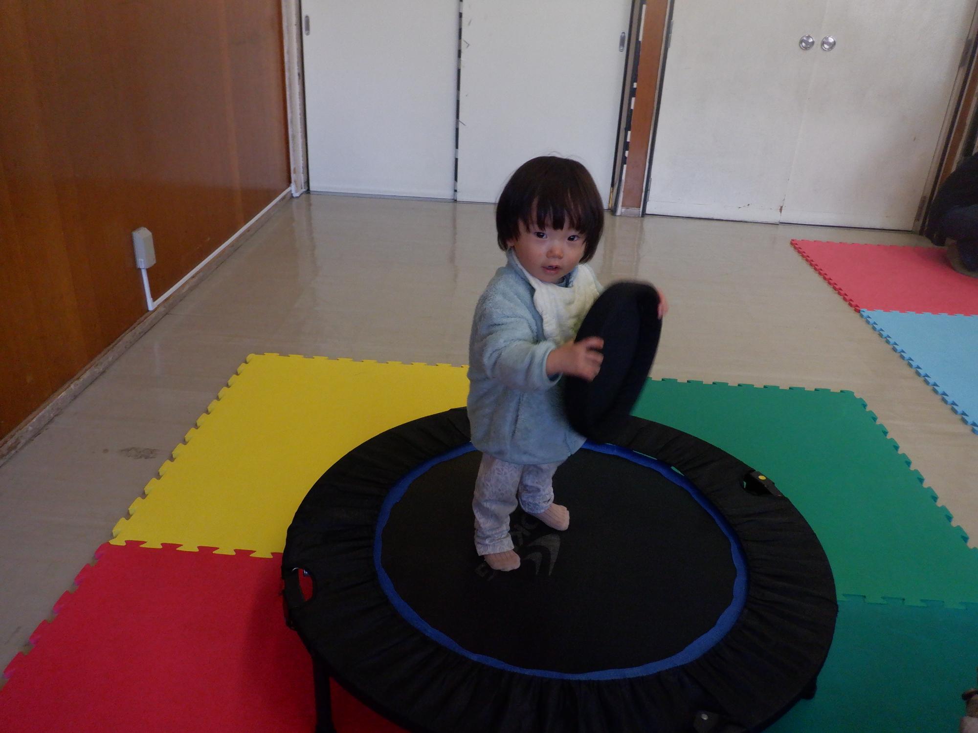 トランポリンの上でカメラ目線を送る幼児