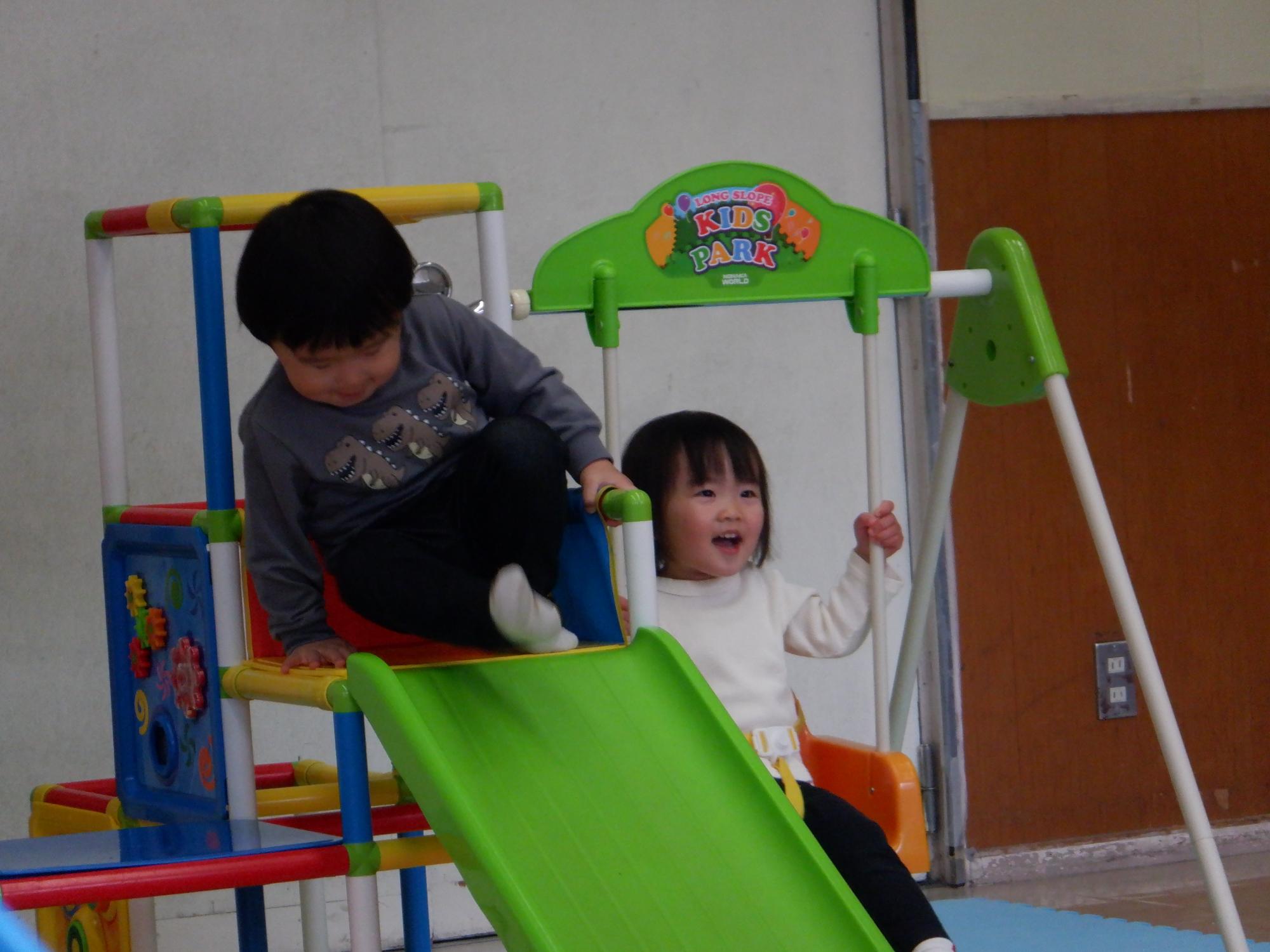 ジャングルジムの滑り台に挑戦する幼児