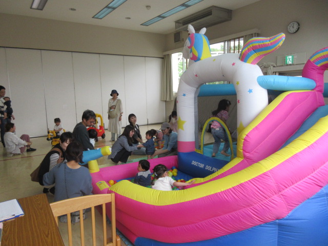 大型エアー遊具の周りで遊ぶ大勢の親子
