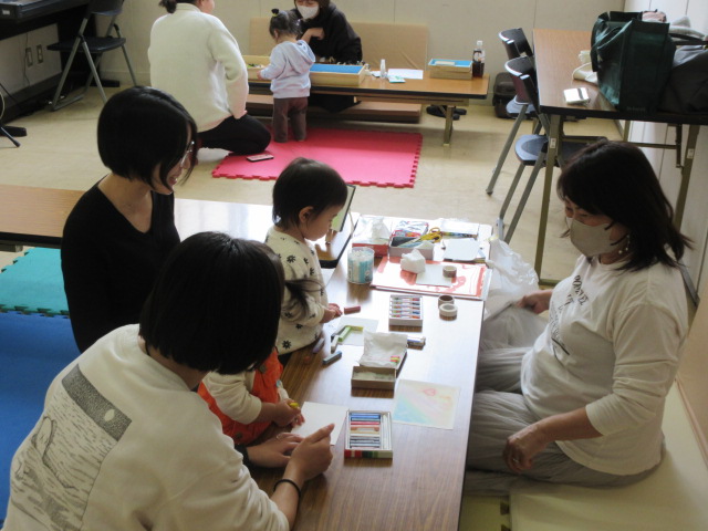 幼児がパステルアートを楽しみながら講師からアドバイスを受けている様子