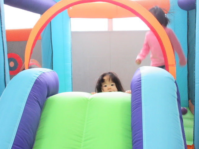 滑り台から顔をのぞかせるこどもの様子