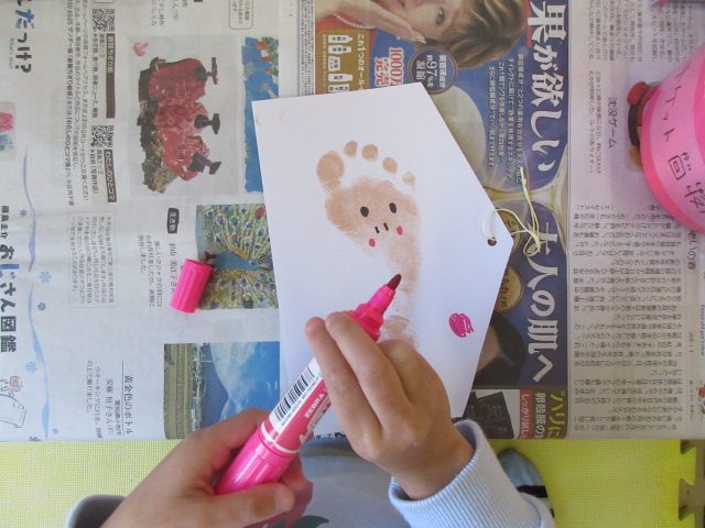 絵馬につけた足型スタンプに絵を描く様子。