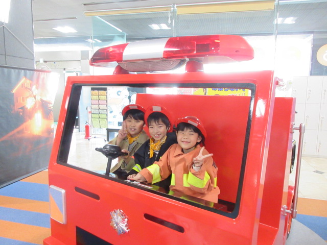 消防士の恰好をして消防車に乗った子どもたち