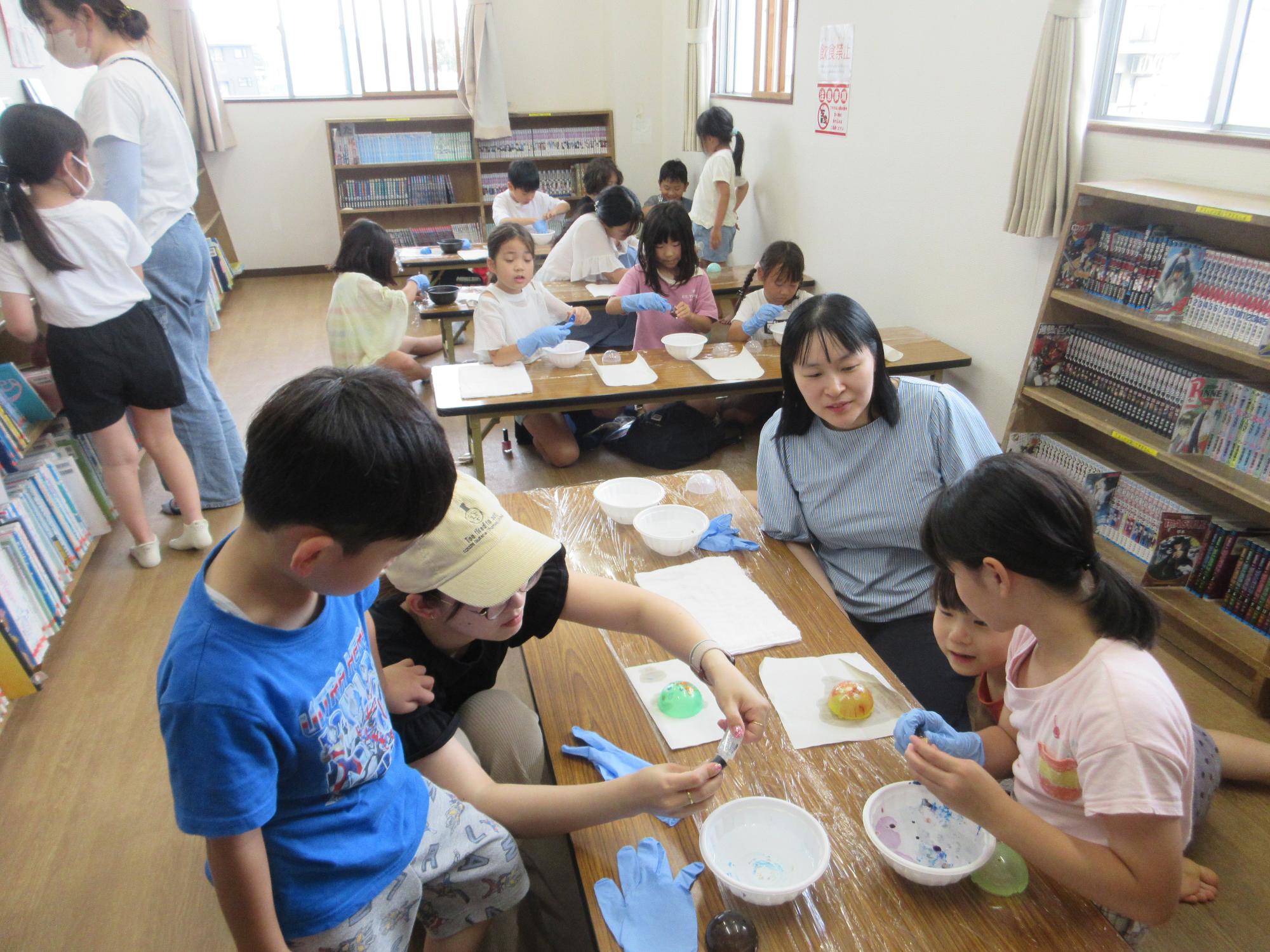 水に落としたマニキュアでカプセルに色をつける子どもたちのようす