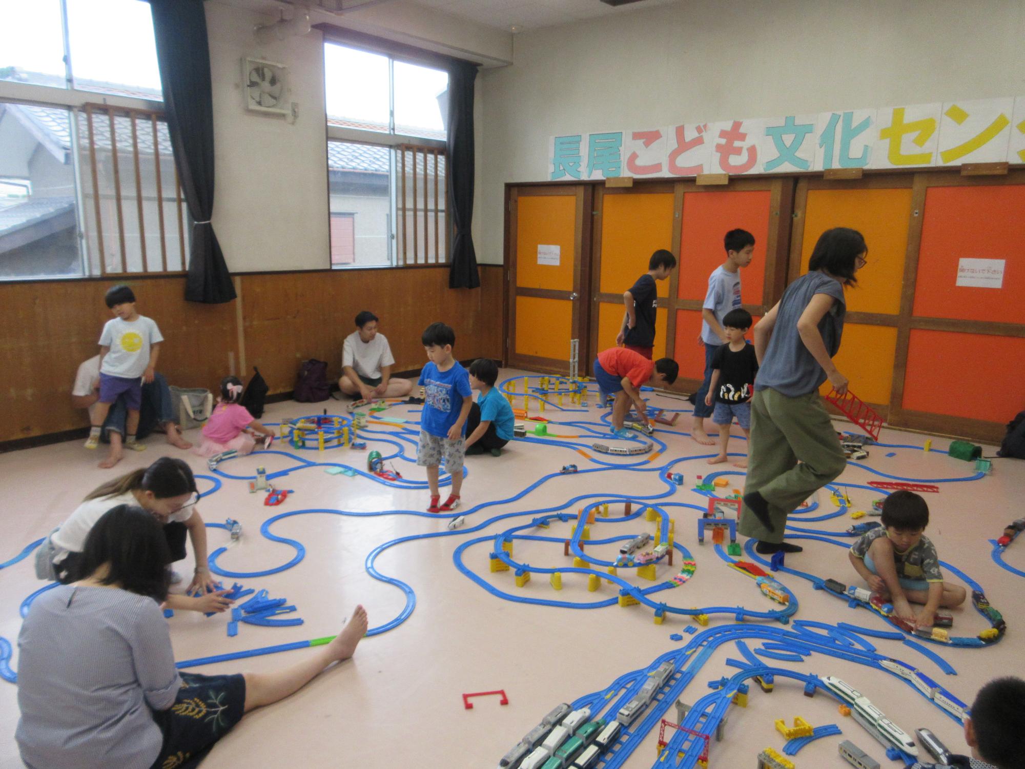 思い思いに線路コースを組む子どもと保護者たちのようす