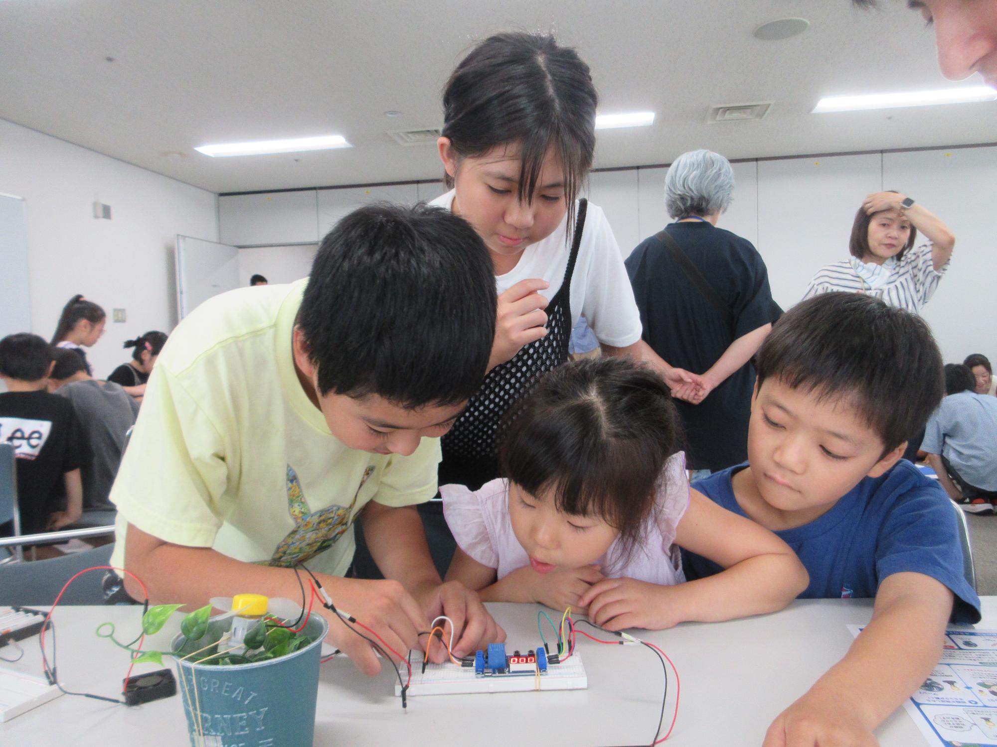机に集まって電子工作をする子どもたち