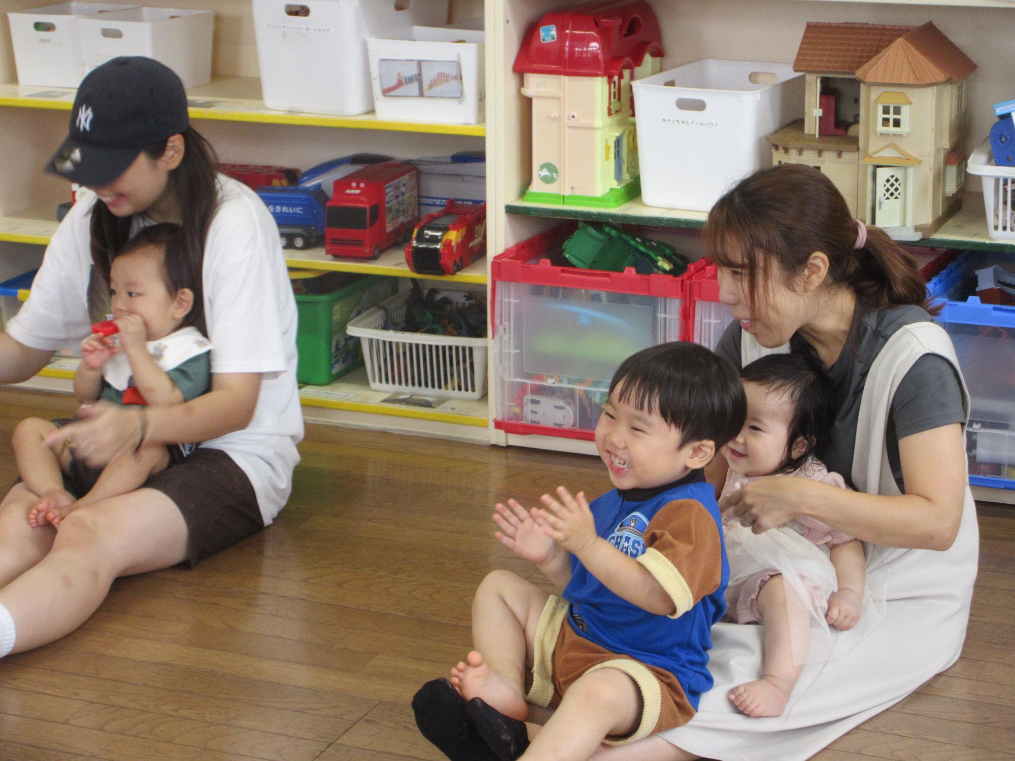 音に合わせて楽しく手をたたく乳幼児親子の様子