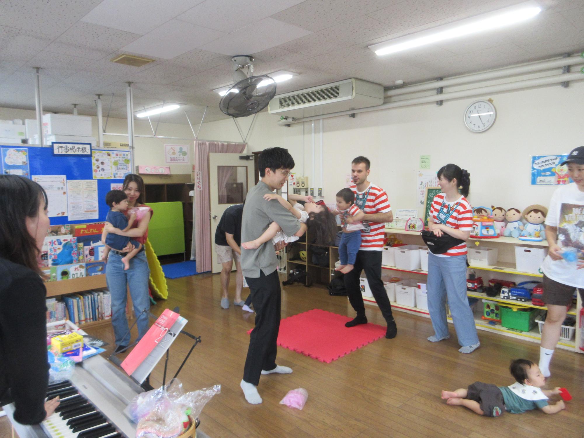 乳幼児親子が数組、音楽に合わせて輪になって動いている様子